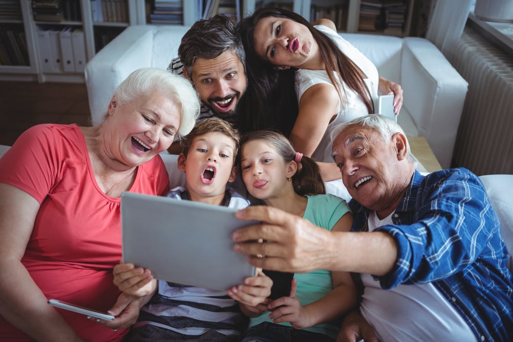 Multi-generation family taking a selfie on digital tablet in living room at home